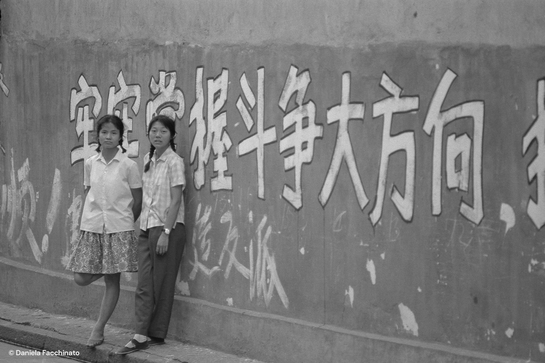 Wuhan, China, 1976. Chinese girls near a mural dazibao